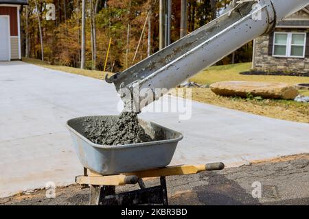 Betonmischwagen gießt während der Bauarbeiten auf der Baustelle feuchten Zement in die Schubkarre Stockfoto