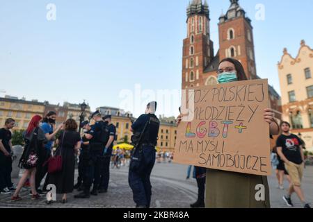 Eine junge Dame hält auf dem Krakauer Hauptmarkt neben dem Adam-Mickiewicz-Denkmal das Schild „70 % der polnischen LGBT + Jugend haben Selbstmordgedanken“. Ein Dutzend junger Aktivisten reagierte mit ihrer Anwesenheit auf eine inoffizielle Facebook-Veranstaltung namens „Regenbogendisko auf dem Hauptplatz“. Nach etwa 15min der Veranstaltung machten Aktivisten ein Gruppenbild am Mickiewicz-Denkmal. Ein paar Minuten später kamen zwei Spuren mit Mitgliedern der örtlichen Polizei und begannen, die Ausweise der Aktivisten zu überprüfen und so der Veranstaltung ein Ende zu setzen. Am Montag, den 12. Freitag, 2020, in Krakau, Polen. (Foto von Artur Widak/NurPhoto) Stockfoto