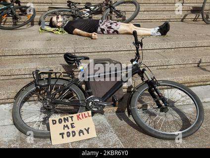 Ein Teilnehmer liegt in der Nähe eines Fahrrads, während Radfahrer am 15. Juni 2020 vor dem Eingang des Rathauses in Kiew, Ukraine, an der Protestaktion „die-in“ teilnehmen, bei der die Straßenverkehrssicherheit und die Verbesserung der Infrastruktur für einen sicheren Radverkehr gefordert werden. Nach Angaben der Aktivisten wurden in den letzten Tagen mehrere Radfahrer und Fußgänger durch die Schuld der Fahrer auf den Straßen von Kiew getötet. (Foto von STR/NurPhoto) Stockfoto