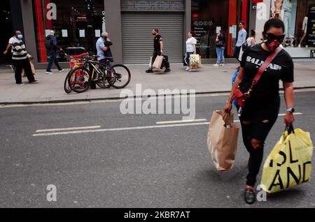 Am 15. Juni 2020 tragen Käufer ihre Taschen entlang der Oxford Street in London, England. Unwesentliche Einzelhandelsgeschäfte in ganz England dürfen heute zum ersten Mal eröffnet werden, seit die Sperre des Coronavirus im März verhängt wurde. Im Zentrum von London waren die Käufer heute Nachmittag in Kraft, mit Schlangen vor vielen Geschäften aufgrund sozialer Distanzierungsanforderungen innerhalb der Geschäfte. (Foto von David Cliff/NurPhoto) Stockfoto