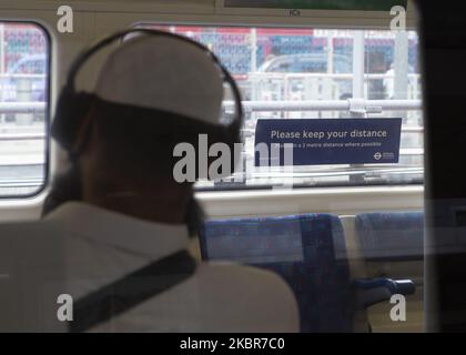 Ein Pendler neben einem sozialen Distanzierungsschild am Bahnhof Stratford in London, England, am 15. 2020. Juni - die Regierung hat ein neues Gesetz durchgesetzt, das es zur Pflicht macht, auf allen öffentlichen Verkehrsmitteln Schutzmasken zu tragen, um die Übertragung von COVID-19 in Großbritannien zu stoppen. (Foto von Jacques Feeney/MI News/NurPhoto) Stockfoto