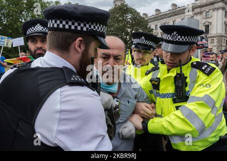 Polizeibeamte verhaften einen pro-kurdischen und anti-Erdogan-Demonstranten in der Nähe des Parlaments, nachdem er vor dem Auto mit dem britischen Premierminister Boris Johnson lief, der nach der Fragestunde der Premierministerin in die Downing Street abfuhr, Das Fahrzeug muss anhalten und anschließend am 17. Juni 2020 in London, England, von hinten vom nächsten Fahrzeug im Konvoi getroffen werden. (Foto von Wiktor Szymanowicz/NurPhoto) Stockfoto