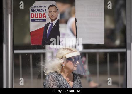 Am 19. Juni 2020 in Warschau, Polen, ist eine Frau zu sehen, die eine Plastikabdeckung auf dem Gesicht hält, die unter einem Plakat für den Präsidentschaftskandidaten Andrzej Duda steht. Am 28. Juni werden die Polen in der ersten Runde der Präsidentschaftswahlen abstimmen. Die Wahlen waren ursprünglich für den 30. Mai geplant, wurden aber aufgrund der Coronavirus-Epidemie annulliert. (Foto von Jaap Arriens/NurPhoto) Stockfoto