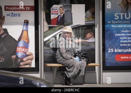 Am 19. Juni 2020 in Warschau, Polen, ist eine Frau zu sehen, die eine Plastikabdeckung auf dem Gesicht hält, die unter einem Plakat für den Präsidentschaftskandidaten Andrzej Duda steht. Am 28. Juni werden die Polen in der ersten Runde der Präsidentschaftswahlen abstimmen. Die Wahlen waren ursprünglich für den 30. Mai geplant, wurden aber aufgrund der Coronavirus-Epidemie annulliert. (Foto von Jaap Arriens/NurPhoto) Stockfoto