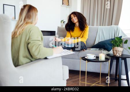 Die junge afroamerikanische Frau hat eine Sitzung mit ihrem Psychologen. Weibliche Patientin mit gemischter Rasse, die in ihrem privaten Beratungszimmer mit der Mentaltrainerin zusammenkommt Stockfoto