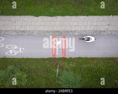 Ein Radfahrer kommt einem Schild auf dem Radweg entgegen, auf dem er davor warnt, am 21. Juni 2020 in Warschau, Polen, Wildenten zu überqueren. Die Verwaltung der Stadtstraßen von Warschau (ZDM) hat Schilder auf Fahrradwegen gemalt, um Radfahrer vor dem Überqueren von Merganser, Wirld Enten zu warnen. Zwischen März und Mai machen wilde Enten die gefährliche Überquerung gegenüber der geschäftigen Czerniakowski Straße von ihrem Teich zur Weichsel. (Foto von Jaap Arriens/NurPhoto) Stockfoto