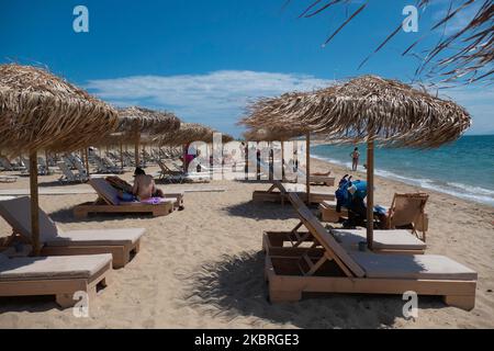 Sandstrand an einem sonnigen Tag und Beach Bar in Nea Irakleia, Chalkidiki in Griechenland mit den ersten Strandbesuchern, die zum Schwimmen und Sonnenbaden kommen. Chalkidiki ist berühmt für den goldenen Sand, das kristallklare, transparente Wasser und den einfachen Zugang zu den Stränden. Strandbars, Hotels und organisierte Strände wurden in Griechenland eröffnet, da die Maßnahmen zur Sperrung durch das Coronavirus Covid-19 in Griechenland aufgehoben wurden und die Tourismusbranche seit Juni 15 durch Öffnung der Grenzen und Aufnahme von Touristen wieder in Gang kommen kann. 22. Juni 2020 (Foto von Nicolas Economou/NurPhoto) Stockfoto