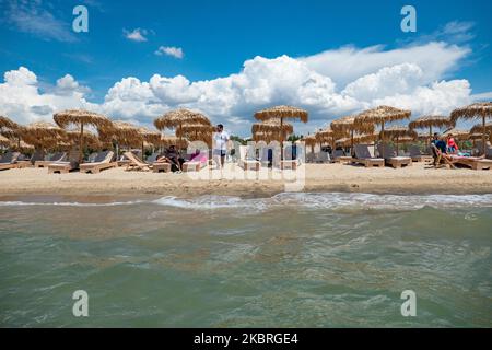 Sandstrand an einem sonnigen Tag und Beach Bar in Nea Irakleia, Chalkidiki in Griechenland mit den ersten Strandbesuchern, die zum Schwimmen und Sonnenbaden kommen. Chalkidiki ist berühmt für den goldenen Sand, das kristallklare, transparente Wasser und den einfachen Zugang zu den Stränden. Strandbars, Hotels und organisierte Strände wurden in Griechenland eröffnet, da die Maßnahmen zur Sperrung durch das Coronavirus Covid-19 in Griechenland aufgehoben wurden und die Tourismusbranche seit Juni 15 durch Öffnung der Grenzen und Aufnahme von Touristen wieder in Gang kommen kann. 22. Juni 2020 (Foto von Nicolas Economou/NurPhoto) Stockfoto