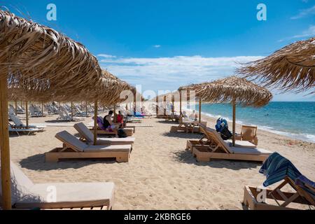 Sandstrand an einem sonnigen Tag und Beach Bar in Nea Irakleia, Chalkidiki in Griechenland mit den ersten Strandbesuchern, die zum Schwimmen und Sonnenbaden kommen. Chalkidiki ist berühmt für den goldenen Sand, das kristallklare, transparente Wasser und den einfachen Zugang zu den Stränden. Strandbars, Hotels und organisierte Strände wurden in Griechenland eröffnet, da die Maßnahmen zur Sperrung durch das Coronavirus Covid-19 in Griechenland aufgehoben wurden und die Tourismusbranche seit Juni 15 durch Öffnung der Grenzen und Aufnahme von Touristen wieder in Gang kommen kann. 22. Juni 2020 (Foto von Nicolas Economou/NurPhoto) Stockfoto