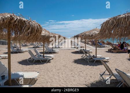 Sandstrand an einem sonnigen Tag und Beach Bar in Nea Irakleia, Chalkidiki in Griechenland mit den ersten Strandbesuchern, die zum Schwimmen und Sonnenbaden kommen. Chalkidiki ist berühmt für den goldenen Sand, das kristallklare, transparente Wasser und den einfachen Zugang zu den Stränden. Strandbars, Hotels und organisierte Strände wurden in Griechenland eröffnet, da die Maßnahmen zur Sperrung durch das Coronavirus Covid-19 in Griechenland aufgehoben wurden und die Tourismusbranche seit Juni 15 durch Öffnung der Grenzen und Aufnahme von Touristen wieder in Gang kommen kann. 22. Juni 2020 (Foto von Nicolas Economou/NurPhoto) Stockfoto