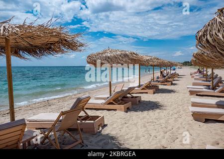 Sandstrand an einem sonnigen Tag und Beach Bar in Nea Irakleia, Chalkidiki in Griechenland mit den ersten Strandbesuchern, die zum Schwimmen und Sonnenbaden kommen. Chalkidiki ist berühmt für den goldenen Sand, das kristallklare, transparente Wasser und den einfachen Zugang zu den Stränden. Strandbars, Hotels und organisierte Strände wurden in Griechenland eröffnet, da die Maßnahmen zur Sperrung durch das Coronavirus Covid-19 in Griechenland aufgehoben wurden und die Tourismusbranche seit Juni 15 durch Öffnung der Grenzen und Aufnahme von Touristen wieder in Gang kommen kann. 22. Juni 2020 (Foto von Nicolas Economou/NurPhoto) Stockfoto