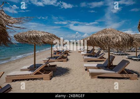 Sandstrand an einem sonnigen Tag und Beach Bar in Nea Irakleia, Chalkidiki in Griechenland mit den ersten Strandbesuchern, die zum Schwimmen und Sonnenbaden kommen. Chalkidiki ist berühmt für den goldenen Sand, das kristallklare, transparente Wasser und den einfachen Zugang zu den Stränden. Strandbars, Hotels und organisierte Strände wurden in Griechenland eröffnet, da die Maßnahmen zur Sperrung durch das Coronavirus Covid-19 in Griechenland aufgehoben wurden und die Tourismusbranche seit Juni 15 durch Öffnung der Grenzen und Aufnahme von Touristen wieder in Gang kommen kann. 22. Juni 2020 (Foto von Nicolas Economou/NurPhoto) Stockfoto