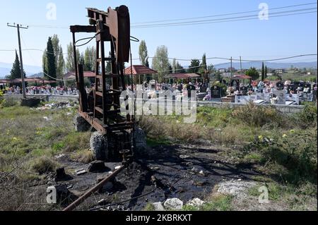 ALBANIEN, Kuçova, benannt Stalin Stadt von 1950 to1991, Rohölfeld und alte Bohrpumpe auf dem Friedhof, immer noch in Betrieb und umweltschädlich / ALBANIEN, Kucova, von 1950 bis 1991 Qyteti Stalin, Stalinstadt, Erdölförderung, alte Oelförderpumpe, die heute noch zur Ölförderung in Betrieb sind, an einem Friedhof Stockfoto
