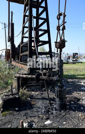 ALBANIEN, Kuçova, benannt Stalin Stadt von 1950 to1991, Rohölfeld und alte Bohrpumpe auf dem Friedhof, immer noch in Betrieb und umweltschädlich / ALBANIEN, Kucova, von 1950 bis 1991 Qyteti Stalin, Stalinstadt, Erdölförderung, alte Oelförderpumpe, die heute noch zur Ölförderung in Betrieb sind, an einem Friedhof Stockfoto