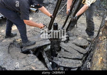 ALBANIEN, Kuçova, benannt Stalin Stadt von 1950 to1991, Rohölfeld und Bohrpumpe aus kommunistischer Zeit, noch in Betrieb und umweltschädlich, Arbeiter mit Bohrrohr / ALBANIEN, Kucova, von 1950 bis 1991 Qyteti Stalin, Stalinstadt, Erdölförderung, alte Oelföerderpumpe, die heute noch zur Ölförderung in Betrieb sind, Work with Bohrgestänge Stockfoto