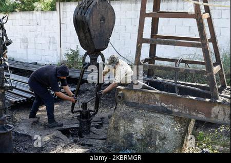 ALBANIEN, Kuçova, benannt Stalin Stadt von 1950 to1991, Rohölfeld und Bohrpumpe aus kommunistischer Zeit, noch in Betrieb und umweltschädlich, Arbeiter mit Bohrrohr / ALBANIEN, Kucova, von 1950 bis 1991 Qyteti Stalin, Stalinstadt, Erdölförderung, alte Oelföerderpumpe, die heute noch zur Ölförderung in Betrieb sind, Work with Bohrgestänge Stockfoto