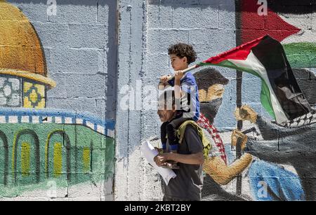 Ein palästinenser mit seinem Sohn, der am 03. Juli 2020 in Rafah im südlichen Gazastreifen in Ramallah in der Westjordanland in der Stadt Ramallah, ein Wandgemälde malt, das eine Sensibilisierungskampagne gegen die geplante Annexion von besetztem palästinensischem Land durch Israel darstellt. An einer Videokonferenz nahmen wir an einem Treffen mit dem stellvertretenden Hamas-Chef Saleh Arouri Teil, bei dem er den Plan Israels diskutierte, Teile des von Israel besetzten Westjordanlands im Juli 2, 2020, zu annektieren.“ Die rivalisierenden palästinensischen Gruppierungen Fatah und Hamas versprachen Einheit gegen Israels Annexionspläne im Westjordanland Stockfoto