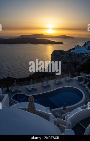 Sonnenuntergang über einem Pool und weiß getünchten Huses. Blick auf den Sonnenuntergang von Thera auf Santorini, Kykladen in der Ägäis in Griechenland. Einige Touristen und Einheimische genießen den magischen Sonnenuntergang über dem Vulkan in Fira, als das Land die Flughäfen öffnete und Touristen nach dem 1. Juli aufgrund der allgemeinen Sperrmaßnahmen des Coronavirus Covid-19, die seit Juni 15 gelockert wurden, die Möglichkeit gab, nach dem Coronavirus zu kommen. Griechenland hat vor kurzem die touristische Sommersaison wieder eröffnet, und Premierminister Kyriakos Mitsotakis hielt während des Sonnenuntergangs eine Rede von Santorin, um die touristische Saison wieder in Gang zu bringen, auf der die griechische Wirtschaft stark basiert Stockfoto