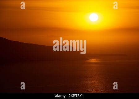 Blick auf den Sonnenuntergang von Thera auf Santorini, Kykladen in der Ägäis in Griechenland. Einige Touristen und Einheimische genießen den magischen Sonnenuntergang über dem Vulkan in Fira, als das Land die Flughäfen öffnete und Touristen nach dem 1. Juli aufgrund der allgemeinen Sperrmaßnahmen des Coronavirus Covid-19, die seit Juni 15 gelockert wurden, die Möglichkeit gab, nach dem Coronavirus zu kommen. Griechenland hat vor kurzem die touristische Sommersaison wieder eröffnet, und Premierminister Kyriakos Mitsotakis hielt während des Sonnenuntergangs eine Rede von Santorin, um die touristische Saison wieder in Gang zu bringen, da die griechische Wirtschaft stark darauf basiert. Juli 2020 (Foto von Nicolas Economou/ Stockfoto