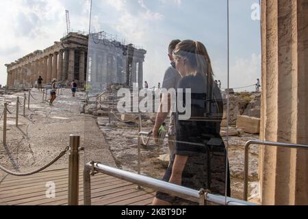 Ankommende Besucher hinter dem Plexiglasteiler. Nur wenige Touristen, die die Akropolis besuchten, verglichen mit der überfüllten Normalität vor der Pandemie, die nach der Lockerung der Covid-19-Coronavirus-Sperrmaßnahmen die wichtigste Sehenswürdigkeit in der griechischen Hauptstadt war. Am Eingang der Akropolis ist ein Trennwand aus Plexiglas installiert. Die Plexiglasbarrieren stehen an Propylaia, während einziehenderen Gurttrenner Touristen zu einer kreisförmigen Route um den Parthenon führen, damit sie keine Gruppen von Angesicht zu Angesicht sehen bekommen. Am 7. Juli 2020 in Athen, Griechenland. (Foto von Nicolas Economou/NurPhoto) Stockfoto