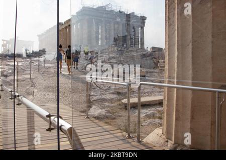 Ankommende Besucher hinter dem Plexiglasteiler. Nur wenige Touristen, die die Akropolis besuchten, verglichen mit der überfüllten Normalität vor der Pandemie, die nach der Lockerung der Covid-19-Coronavirus-Sperrmaßnahmen die wichtigste Sehenswürdigkeit in der griechischen Hauptstadt war. Am Eingang der Akropolis ist ein Trennwand aus Plexiglas installiert. Die Plexiglasbarrieren stehen an Propylaia, während einziehenderen Gurttrenner Touristen zu einer kreisförmigen Route um den Parthenon führen, damit sie keine Gruppen von Angesicht zu Angesicht sehen bekommen. Am 7. Juli 2020 in Athen, Griechenland. Es gibt nur wenige Touristen, die die Akropolis besuchen, wenn man die T-Stadt vergleicht Stockfoto