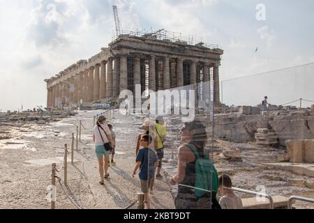 Ankommende Besucher hinter dem Plexiglasteiler. Nur wenige Touristen, die die Akropolis besuchten, verglichen mit der überfüllten Normalität vor der Pandemie, die nach der Lockerung der Covid-19-Coronavirus-Sperrmaßnahmen die wichtigste Sehenswürdigkeit in der griechischen Hauptstadt war. Am Eingang der Akropolis ist ein Trennwand aus Plexiglas installiert. Die Plexiglasbarrieren stehen an Propylaia, während einziehenderen Gurttrenner Touristen zu einer kreisförmigen Route um den Parthenon führen, damit sie keine Gruppen von Angesicht zu Angesicht sehen bekommen. Am 7. Juli 2020 in Athen, Griechenland. Es gibt nur wenige Touristen, die die Akropolis besuchen, wenn man die T-Stadt vergleicht Stockfoto