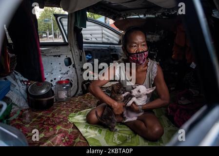 Christina Dela Cruz, 49, spielt mit ihren Welpen in einem verlassenen Auto, das am 9. Juli 2020 in Manila, Philippinen, als provisorische Heimat dient. Dela Cruz und ihr Partner, Ramil Mañanita, 39, verließen ihr Miethaus ebenfalls in Manila, nachdem sie 5 Monate Mietgebühr nicht bezahlt hatten. Ohne einen Job aufgrund der Sperre lässt das Paar die Enden treffen, indem es Plastikflaschen aufholt und diese an Junk-Shops verkauft. Das Paar mit ihrer Katze und vier Welpen lebt seit April in dem zerstörten Auto.(Foto: Lisa Marie David/NurPhoto) Stockfoto