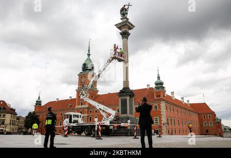 Cityhall-Arbeiter entfernen einen Schal des Fußballvereins Legia Warszawa, der illegal von Fußballfans auf einer markanten hohen Säulenstatue des polnischen Königs Zygmunt III Waza (Sigismund-Säule) aufgestellt wurde, da Legia Warszawa die Meisterschaften Polens am 11. Juli gewonnen hat - Warschau, Polen, 13. Juli 2020. Die Säule ist mehr als 10 Meter hoch und die Polizei kann nicht angeben, wie der Schal auf den Hals der Statue gelegt wurde. (Foto von Dominika Zarzycka/NurPhoto) Stockfoto