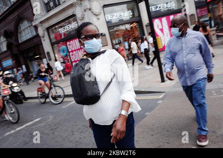 Ein Mann und eine Frau mit Gesichtsmasken durchqueren am 22. Juli 2020 den Oxford Circus in London, England. Die Verkaufsdaten des britischen Einzelhandels für den Juni, in dem nicht unbedingt erforderliche Geschäfte wieder eröffnet werden konnten, werden voraussichtlich am Freitag, den 24. Juli, vom Office for National Statistics (ONS) veröffentlicht. Der Tag wird auch der erste sein, an dem die Menschen in England in Geschäften und Supermärkten Gesichtsmasken oder andere Arten von Gesichtsbedeckungen tragen müssen. Seit Mitte Juni sind Gesichtsbedeckungen im öffentlichen Verkehr in ganz England obligatorisch. (Foto von David Cliff/NurPhoto) Stockfoto