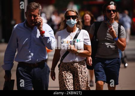 Eine Frau mit Gesichtsmaske geht am 22. Juli 2020 in der Oxford Street in London, England, inmitten von Einkäufern spazieren. Die Verkaufsdaten des britischen Einzelhandels für den Juni, in dem nicht unbedingt erforderliche Geschäfte wieder eröffnet werden konnten, werden voraussichtlich am Freitag, den 24. Juli, vom Office for National Statistics (ONS) veröffentlicht. Der Tag wird auch der erste sein, an dem die Menschen in England in Geschäften und Supermärkten Gesichtsmasken oder andere Arten von Gesichtsbedeckungen tragen müssen. Seit Mitte Juni sind Gesichtsbedeckungen im öffentlichen Verkehr in ganz England obligatorisch. (Foto von David Cliff/NurPhoto) Stockfoto