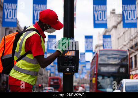 Ein Arbeiter desinfiziert am 22. Juli 2020 das Bedienfeld einer Fußgängerüberführung in der Regent Street in London, England. Die Verkaufsdaten des britischen Einzelhandels für den Juni, in dem nicht unbedingt erforderliche Geschäfte wieder eröffnet werden konnten, werden voraussichtlich am Freitag, den 24. Juli, vom Office for National Statistics (ONS) veröffentlicht. Der Tag wird auch der erste sein, an dem die Menschen in England in Geschäften und Supermärkten Gesichtsmasken oder andere Arten von Gesichtsbedeckungen tragen müssen. Seit Mitte Juni sind Gesichtsbedeckungen im öffentlichen Verkehr in ganz England obligatorisch. (Foto von David Cliff/NurPhoto) Stockfoto