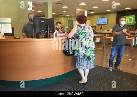 Bankverteller dienen Kunden, die hinter Plexiglas (Kunststoff)-Barrieren stehen, um sie am 23. Juli 2020 in Toronto, Ontario, Kanada, vor dem neuartigen Coronavirus (COVID-19) zu schützen. (Foto von Creative Touch Imaging Ltd./NurPhoto) Stockfoto