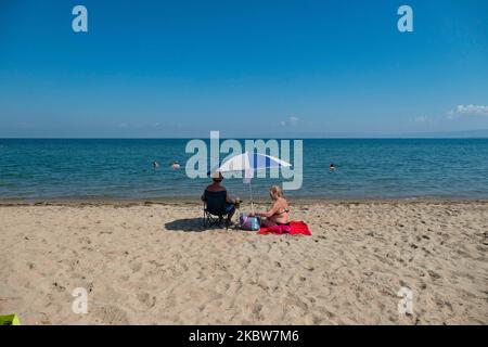 Alltag am Sandstrand von Agia Triada in der Nähe von Thessaloniki in Griechenland am 26. Juli 2020. Agia Triada ist ein Sommer-Touristenziel für Einheimische und ausländische Touristen für Ferien vor allem aus den Balkanländern. Der Strand ist mit der Blauen Flagge ausgezeichnet, hat typisch für griechische Strände und die Ägäis, kristallklares, transparentes Meerwasser, goldenen Sand und viele touristische Einrichtungen wie eine Fußgängerzone Uferstraße neben dem Ufer, kostenlose Duschen usw. Es gibt Hotels, Tavernen, Restaurants, Bars und Strandbars in der Gegend, die nur ein paar Minuten Fahrt vom internationalen Flughafen Thessaloniki entfernt ist Stockfoto