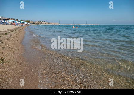 Alltag am Sandstrand von Agia Triada in der Nähe von Thessaloniki in Griechenland am 26. Juli 2020. Agia Triada ist ein Sommer-Touristenziel für Einheimische und ausländische Touristen für Ferien vor allem aus den Balkanländern. Der Strand ist mit der Blauen Flagge ausgezeichnet, hat typisch für griechische Strände und die Ägäis, kristallklares, transparentes Meerwasser, goldenen Sand und viele touristische Einrichtungen wie eine Fußgängerzone Uferstraße neben dem Ufer, kostenlose Duschen usw. Es gibt Hotels, Tavernen, Restaurants, Bars und Strandbars in der Gegend, die nur ein paar Minuten Fahrt vom internationalen Flughafen Thessaloniki entfernt ist Stockfoto