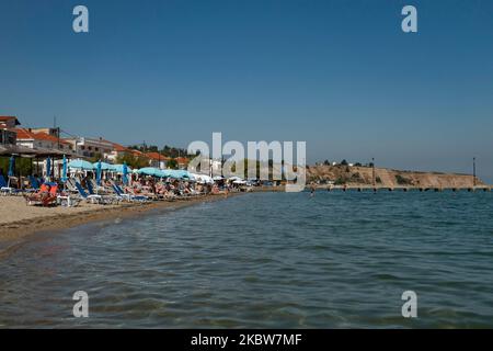 Alltag am Sandstrand von Agia Triada in der Nähe von Thessaloniki in Griechenland am 26. Juli 2020. Agia Triada ist ein Sommer-Touristenziel für Einheimische und ausländische Touristen für Ferien vor allem aus den Balkanländern. Der Strand ist mit der Blauen Flagge ausgezeichnet, hat typisch für griechische Strände und die Ägäis, kristallklares, transparentes Meerwasser, goldenen Sand und viele touristische Einrichtungen wie eine Fußgängerzone Uferstraße neben dem Ufer, kostenlose Duschen usw. Es gibt Hotels, Tavernen, Restaurants, Bars und Strandbars in der Gegend, die nur ein paar Minuten Fahrt vom internationalen Flughafen Thessaloniki entfernt ist Stockfoto