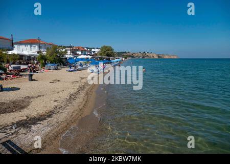 Alltag am Sandstrand von Agia Triada in der Nähe von Thessaloniki in Griechenland am 26. Juli 2020. Agia Triada ist ein Sommer-Touristenziel für Einheimische und ausländische Touristen für Ferien vor allem aus den Balkanländern. Der Strand ist mit der Blauen Flagge ausgezeichnet, hat typisch für griechische Strände und die Ägäis, kristallklares, transparentes Meerwasser, goldenen Sand und viele touristische Einrichtungen wie eine Fußgängerzone Uferstraße neben dem Ufer, kostenlose Duschen usw. Es gibt Hotels, Tavernen, Restaurants, Bars und Strandbars in der Gegend, die nur ein paar Minuten Fahrt vom internationalen Flughafen Thessaloniki entfernt ist Stockfoto