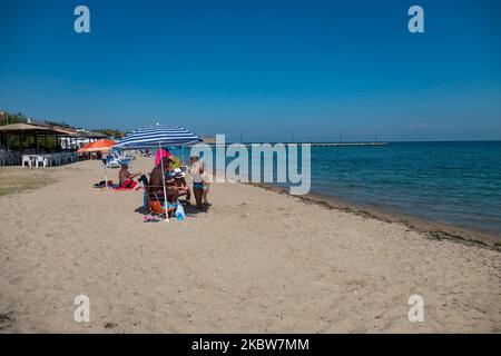 Alltag am Sandstrand von Agia Triada in der Nähe von Thessaloniki in Griechenland am 26. Juli 2020. Agia Triada ist ein Sommer-Touristenziel für Einheimische und ausländische Touristen für Ferien vor allem aus den Balkanländern. Der Strand ist mit der Blauen Flagge ausgezeichnet, hat typisch für griechische Strände und die Ägäis, kristallklares, transparentes Meerwasser, goldenen Sand und viele touristische Einrichtungen wie eine Fußgängerzone Uferstraße neben dem Ufer, kostenlose Duschen usw. Es gibt Hotels, Tavernen, Restaurants, Bars und Strandbars in der Gegend, die nur ein paar Minuten Fahrt vom internationalen Flughafen Thessaloniki entfernt ist Stockfoto