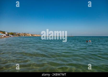 Alltag am Sandstrand von Agia Triada in der Nähe von Thessaloniki in Griechenland am 26. Juli 2020. Agia Triada ist ein Sommer-Touristenziel für Einheimische und ausländische Touristen für Ferien vor allem aus den Balkanländern. Der Strand ist mit der Blauen Flagge ausgezeichnet, hat typisch für griechische Strände und die Ägäis, kristallklares, transparentes Meerwasser, goldenen Sand und viele touristische Einrichtungen wie eine Fußgängerzone Uferstraße neben dem Ufer, kostenlose Duschen usw. Es gibt Hotels, Tavernen, Restaurants, Bars und Strandbars in der Gegend, die nur ein paar Minuten Fahrt vom internationalen Flughafen Thessaloniki entfernt ist Stockfoto