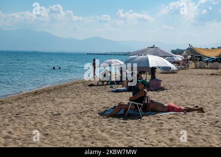 Alltag am Sandstrand von Agia Triada in der Nähe von Thessaloniki in Griechenland am 26. Juli 2020. Agia Triada ist ein Sommer-Touristenziel für Einheimische und ausländische Touristen für Ferien vor allem aus den Balkanländern. Der Strand ist mit der Blauen Flagge ausgezeichnet, hat typisch für griechische Strände und die Ägäis, kristallklares, transparentes Meerwasser, goldenen Sand und viele touristische Einrichtungen wie eine Fußgängerzone Uferstraße neben dem Ufer, kostenlose Duschen usw. Es gibt Hotels, Tavernen, Restaurants, Bars und Strandbars in der Gegend, die nur ein paar Minuten Fahrt vom internationalen Flughafen Thessaloniki entfernt ist Stockfoto