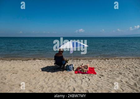 Alltag am Sandstrand von Agia Triada in der Nähe von Thessaloniki in Griechenland am 26. Juli 2020. Agia Triada ist ein Sommer-Touristenziel für Einheimische und ausländische Touristen für Ferien vor allem aus den Balkanländern. Der Strand ist mit der Blauen Flagge ausgezeichnet, hat typisch für griechische Strände und die Ägäis, kristallklares, transparentes Meerwasser, goldenen Sand und viele touristische Einrichtungen wie eine Fußgängerzone Uferstraße neben dem Ufer, kostenlose Duschen usw. Es gibt Hotels, Tavernen, Restaurants, Bars und Strandbars in der Gegend, die nur ein paar Minuten Fahrt vom internationalen Flughafen Thessaloniki entfernt ist Stockfoto