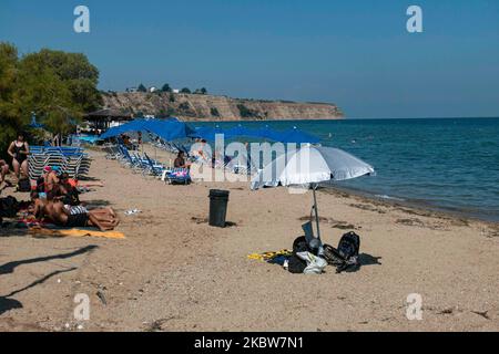 Alltag am Sandstrand von Agia Triada in der Nähe von Thessaloniki in Griechenland am 26. Juli 2020. Agia Triada ist ein Sommer-Touristenziel für Einheimische und ausländische Touristen für Ferien vor allem aus den Balkanländern. Der Strand ist mit der Blauen Flagge ausgezeichnet, hat typisch für griechische Strände und die Ägäis, kristallklares, transparentes Meerwasser, goldenen Sand und viele touristische Einrichtungen wie eine Fußgängerzone Uferstraße neben dem Ufer, kostenlose Duschen usw. Es gibt Hotels, Tavernen, Restaurants, Bars und Strandbars in der Gegend, die nur ein paar Minuten Fahrt vom internationalen Flughafen Thessaloniki entfernt ist Stockfoto