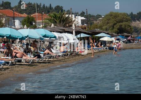 Alltag am Sandstrand von Agia Triada in der Nähe von Thessaloniki in Griechenland am 26. Juli 2020. Agia Triada ist ein Sommer-Touristenziel für Einheimische und ausländische Touristen für Ferien vor allem aus den Balkanländern. Der Strand ist mit der Blauen Flagge ausgezeichnet, hat typisch für griechische Strände und die Ägäis, kristallklares, transparentes Meerwasser, goldenen Sand und viele touristische Einrichtungen wie eine Fußgängerzone Uferstraße neben dem Ufer, kostenlose Duschen usw. Es gibt Hotels, Tavernen, Restaurants, Bars und Strandbars in der Gegend, die nur ein paar Minuten Fahrt vom internationalen Flughafen Thessaloniki entfernt ist Stockfoto
