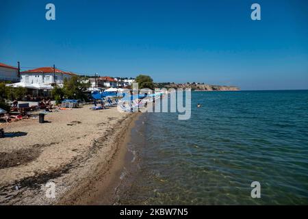 Alltag am Sandstrand von Agia Triada in der Nähe von Thessaloniki in Griechenland am 26. Juli 2020. Agia Triada ist ein Sommer-Touristenziel für Einheimische und ausländische Touristen für Ferien vor allem aus den Balkanländern. Der Strand ist mit der Blauen Flagge ausgezeichnet, hat typisch für griechische Strände und die Ägäis, kristallklares, transparentes Meerwasser, goldenen Sand und viele touristische Einrichtungen wie eine Fußgängerzone Uferstraße neben dem Ufer, kostenlose Duschen usw. Es gibt Hotels, Tavernen, Restaurants, Bars und Strandbars in der Gegend, die nur ein paar Minuten Fahrt vom internationalen Flughafen Thessaloniki entfernt ist Stockfoto