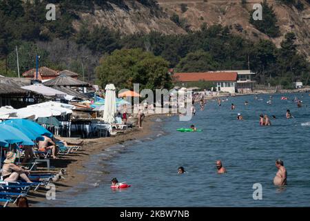 Alltag am Sandstrand von Agia Triada in der Nähe von Thessaloniki in Griechenland am 26. Juli 2020. Agia Triada ist ein Sommer-Touristenziel für Einheimische und ausländische Touristen für Ferien vor allem aus den Balkanländern. Der Strand ist mit der Blauen Flagge ausgezeichnet, hat typisch für griechische Strände und die Ägäis, kristallklares, transparentes Meerwasser, goldenen Sand und viele touristische Einrichtungen wie eine Fußgängerzone Uferstraße neben dem Ufer, kostenlose Duschen usw. Es gibt Hotels, Tavernen, Restaurants, Bars und Strandbars in der Gegend, die nur ein paar Minuten Fahrt vom internationalen Flughafen Thessaloniki entfernt ist Stockfoto