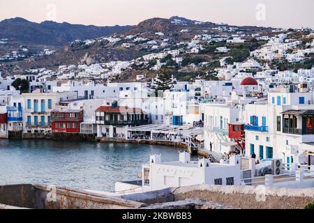 Magische Stunde bei Sonnenuntergang und Abenddämmerung in Little Venice auf Mykonos, einem der romantischsten Orte der Mittelmeerinsel am 14. Juli 2020. Dieses Viertel ist voll von eleganten und wunderschönen alten Häusern, die sich prekär am Rande der Ägäis befinden, farbenfrohe zweistöckige Gebäude im venezianischen Stil mit Holzbalkons. Diese Gebäude beherbergen heute trendige Bars, Restaurants, Galerien und mehr, aber ihr Äußeres ist immer noch einer der beliebtesten Sonnenuntergangsorte, das klassische romantische Mykonos-Erlebnis. Die berühmte Insel in den Kykladen wird als die Insel der Wi benannt Stockfoto