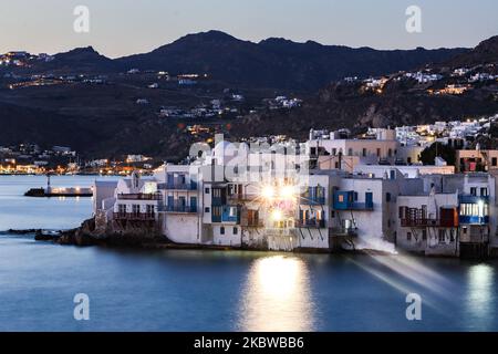 Magische Stunde bei Sonnenuntergang und Abenddämmerung in Little Venice auf Mykonos, einem der romantischsten Orte der Mittelmeerinsel am 14. Juli 2020. Dieses Viertel ist voll von eleganten und wunderschönen alten Häusern, die sich prekär am Rande der Ägäis befinden, farbenfrohe zweistöckige Gebäude im venezianischen Stil mit Holzbalkons. Diese Gebäude beherbergen heute trendige Bars, Restaurants, Galerien und mehr, aber ihr Äußeres ist immer noch einer der beliebtesten Sonnenuntergangsorte, das klassische romantische Mykonos-Erlebnis. Die berühmte Insel in den Kykladen wird als die Insel der Wi benannt Stockfoto