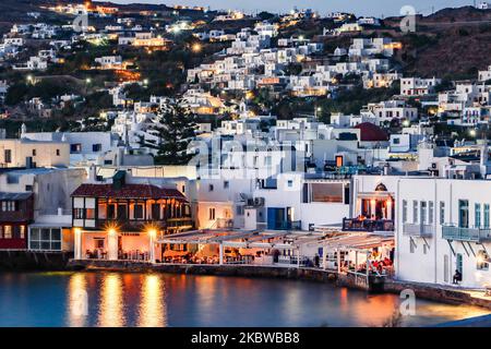 Magische Stunde bei Sonnenuntergang und Abenddämmerung in Little Venice auf Mykonos, einem der romantischsten Orte der Mittelmeerinsel am 14. Juli 2020. Dieses Viertel ist voll von eleganten und wunderschönen alten Häusern, die sich prekär am Rande der Ägäis befinden, farbenfrohe zweistöckige Gebäude im venezianischen Stil mit Holzbalkons. Diese Gebäude beherbergen heute trendige Bars, Restaurants, Galerien und mehr, aber ihr Äußeres ist immer noch einer der beliebtesten Sonnenuntergangsorte, das klassische romantische Mykonos-Erlebnis. Die berühmte Insel in den Kykladen wird als die Insel der Wi benannt Stockfoto