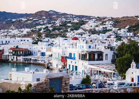 Magische Stunde bei Sonnenuntergang und Abenddämmerung in Little Venice auf Mykonos, einem der romantischsten Orte der Mittelmeerinsel am 14. Juli 2020. Dieses Viertel ist voll von eleganten und wunderschönen alten Häusern, die sich prekär am Rande der Ägäis befinden, farbenfrohe zweistöckige Gebäude im venezianischen Stil mit Holzbalkons. Diese Gebäude beherbergen heute trendige Bars, Restaurants, Galerien und mehr, aber ihr Äußeres ist immer noch einer der beliebtesten Sonnenuntergangsorte, das klassische romantische Mykonos-Erlebnis. Die berühmte Insel in den Kykladen wird als die Insel der Wi benannt Stockfoto