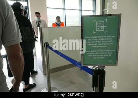 Flug vom internationalen Flughafen Mykonos JMK LGMK in Griechenland. Passagiere mit Gesichtsmasken und Schutzmaßnahmen wie Handschuhen, Händedesinfektionsmittel, Sitzblockierung, sozialen Distanzschildern usw. aufgrund der Pandemiemaßnahmen des Coronavirus Covid-19, wie sie an den Check-in-Schaltern, am Hauptabfluganschluss, an den Gates und beim Hingehen zum Flugzeug zu sehen sind, Ein Olympic Air Turboprop-Flugzeug Bombardier DHC-8-400 mit der Registrierung SX-OBA. Der Flughafen gehört der griechischen Regierung, wird aber seit dem 11. April 2017 nach den Privatisierungsbemühungen von 2015 von Fraport Greece betrieben. Am 29. Juli 2020 in Mykonos Stockfoto