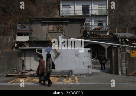 25. März 2011-Kamaishi, Japan-Überlebende der Ureinwohner, die ihr Haus auf Trümmern und Schlamm verlassen, der bei einem Tsunami bedeckt war, zerstörten am 25. März 2011 in Kamaishi die Minenstadt in Japan. Am 11. März 2011 ereignete sich in Japan ein Erdbeben mit einer Magnitude von 9,0, dem größten in der Geschichte des Landes und einem der fünf mächtigsten, die jemals auf der ganzen Welt verzeichnet wurden. Innerhalb einer Stunde nach dem Erdbeben wurden die Städte, die das Ufer säumten, durch einen massiven Tsunami abgeflacht, der durch die Energie verursacht wurde, die durch das Erdbeben freigesetzt wurde. Mit Wellen von bis zu vier oder fünf Metern Höhe stürzten sie durch Häuser, Städte und Felder der Zivilbevölkerung. (Phot Stockfoto